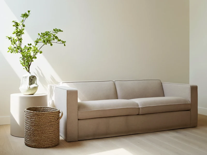 Heller Wohnbereich mit Leinensofa, Korb und Keramikvase im Morgenlicht
